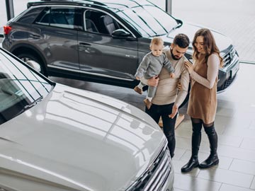 Eine Familie erkundet bei Autoankauf Rostock und bewundert ein weißes Fahrzeug, während ein stilvoller SUV im Hintergrund in einem modernen Showroom zu sehen ist.